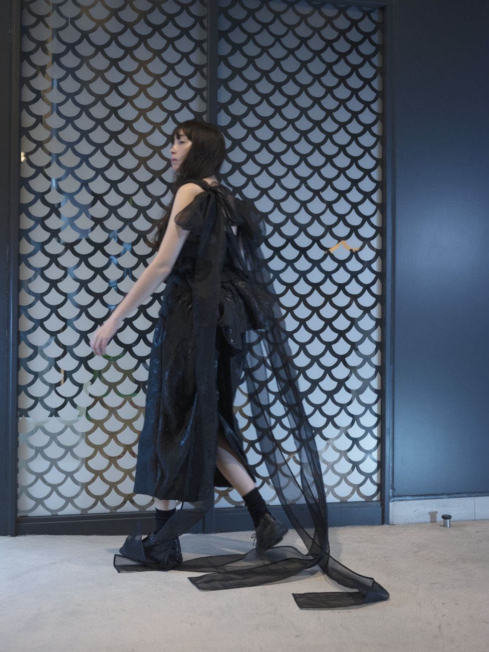 un mannequin porte une robe noire cecilie bahnsen avec des baskets asics