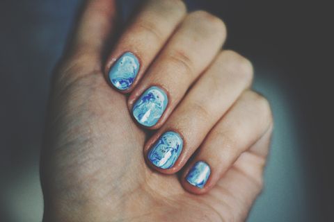 ongles peints en bleu clair et ornés d'un motif en marbre bleu foncé
