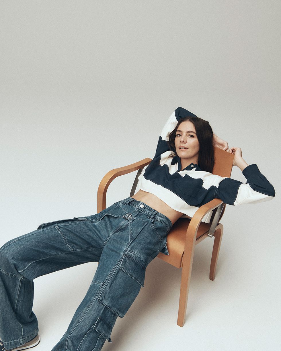 molly dickson est assise sur une chaise portant un jean cargo et une chemise de rugby dans un guide de sa collaboration en denim avec madewell