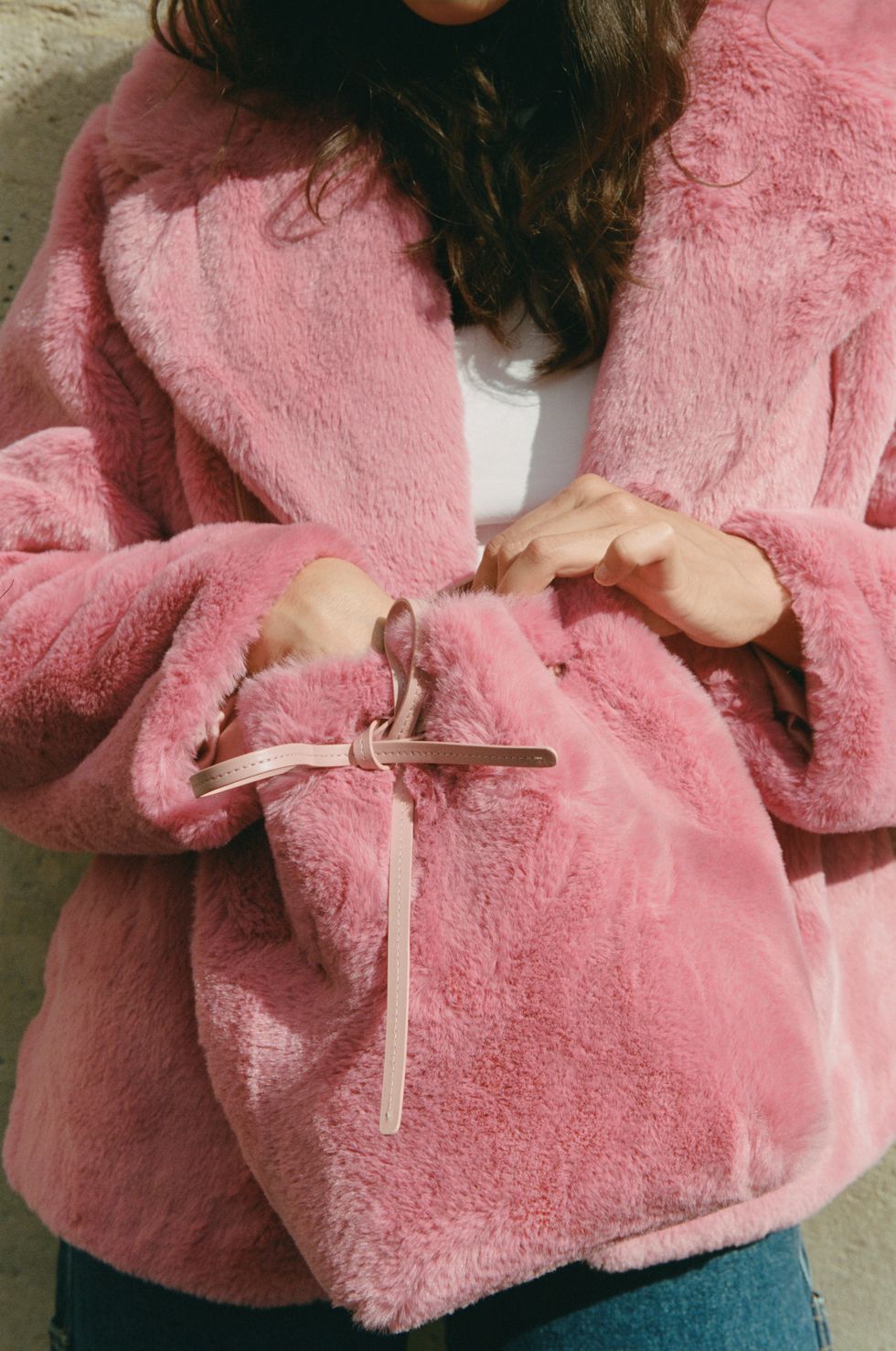 un mannequin porte un manteau en fausse fourrure rose tenant un sac assorti