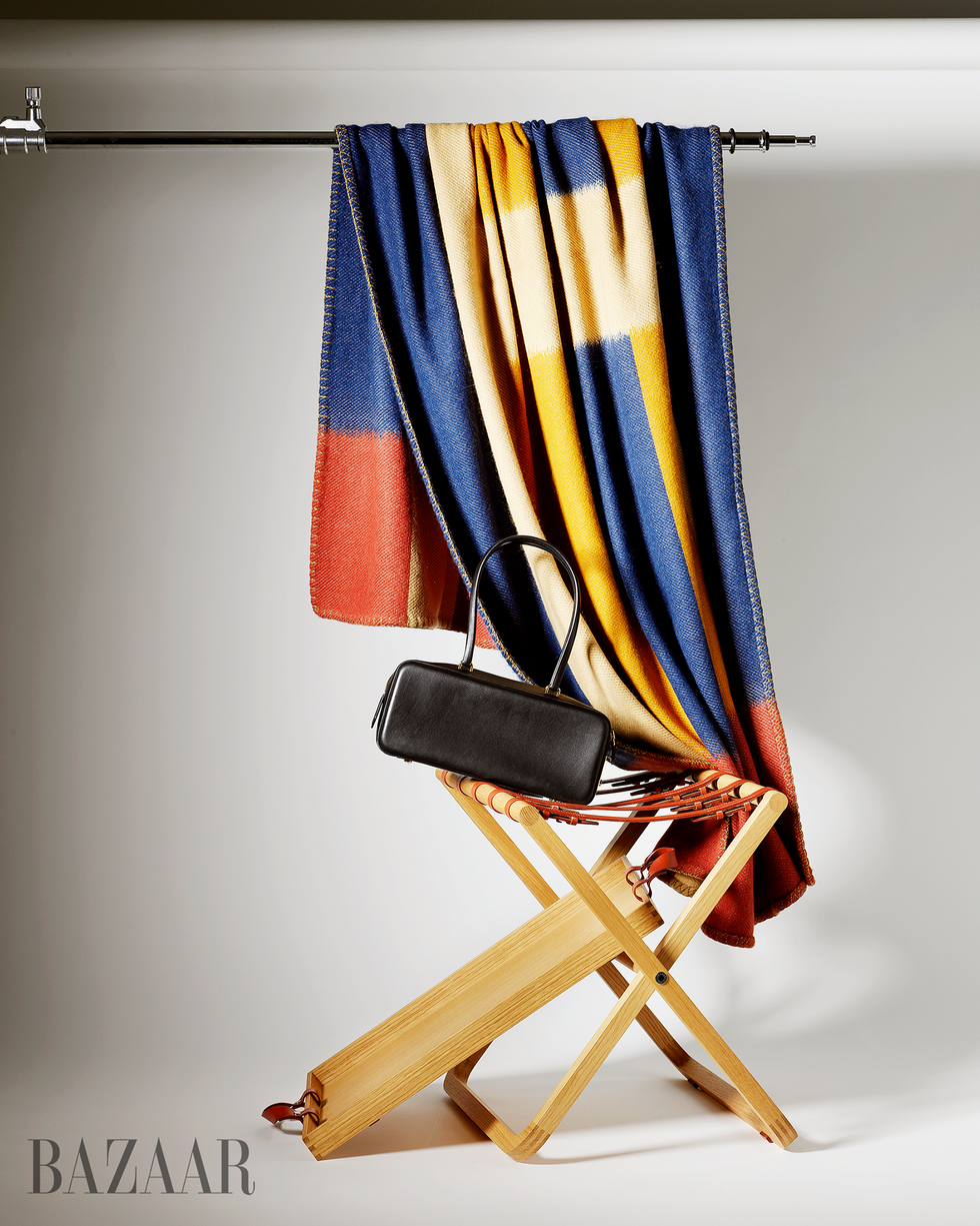 Une couverture pliée drapée sur une chaise en bois à côté d'un petit sac à main noir