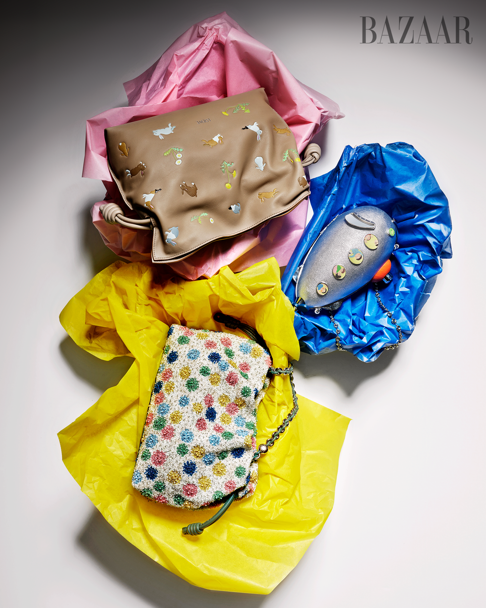 Divers sacs à main de créateurs disposés sur du papier de soie coloré