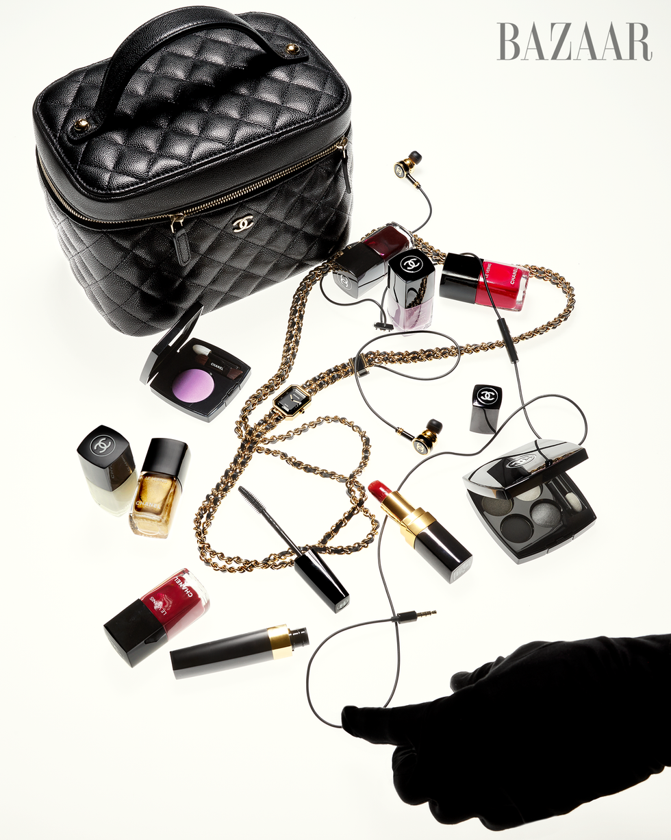 Sac à main matelassé noir entouré de produits de maquillage et d'accessoires