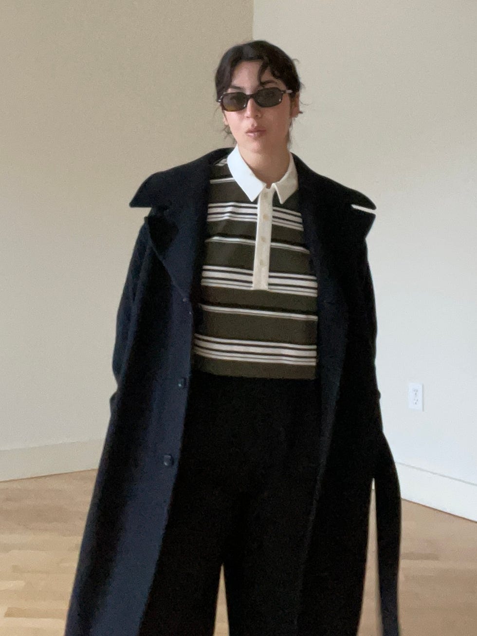 personne portant un polo rayé et un long manteau noir