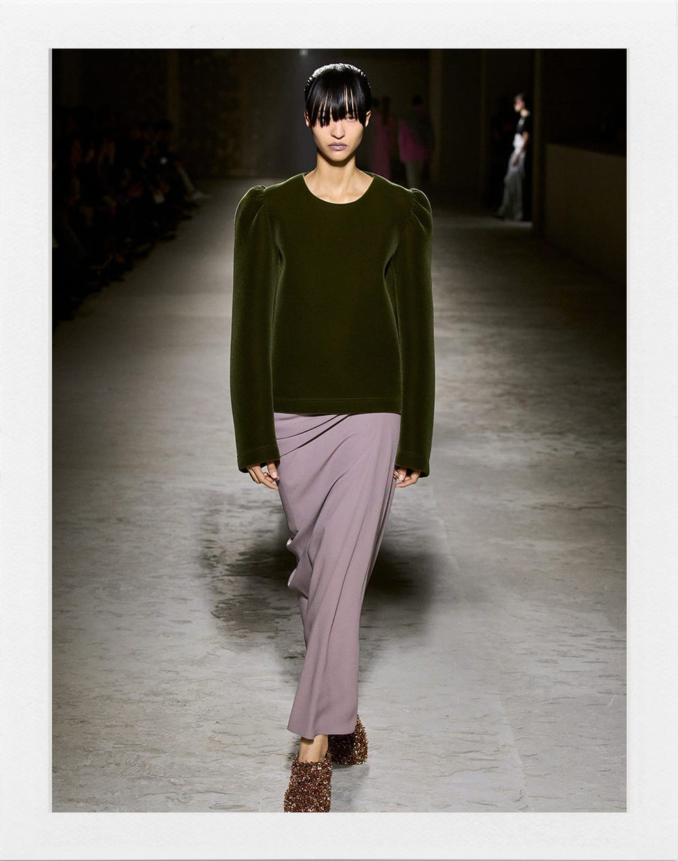 un modèle portant un haut vert et une jupe lavande sur une piste