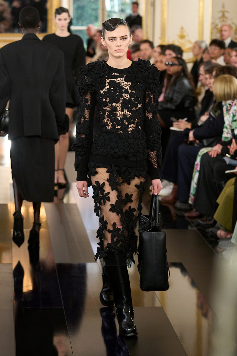 Fashion Runway présentant un modèle dans une tenue florale noire et des bottes à genoux