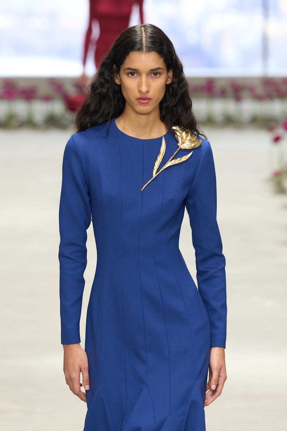 Un modèle marche sur la piste dans une robe bleue avec un orage d'or