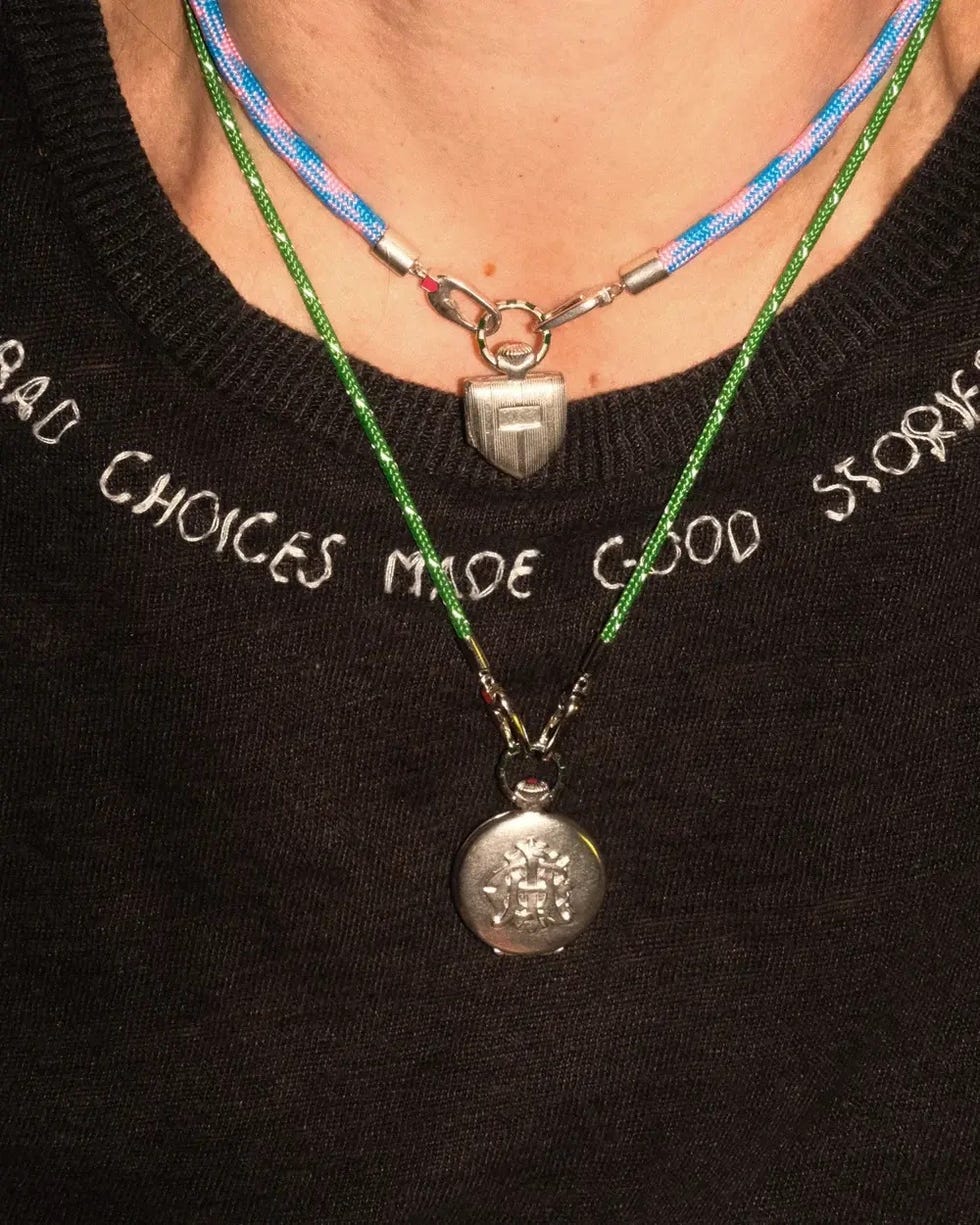 Colliers en couches portés par une personne avec un pendentif bouclier et un charme circulaire