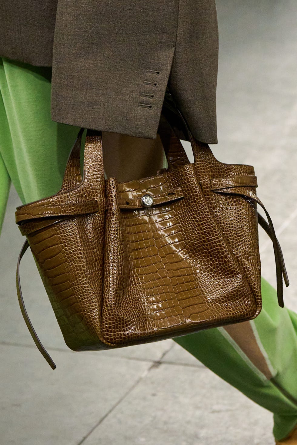 Sac à main en cuir brun crocodile porté avec une tenue à la mode