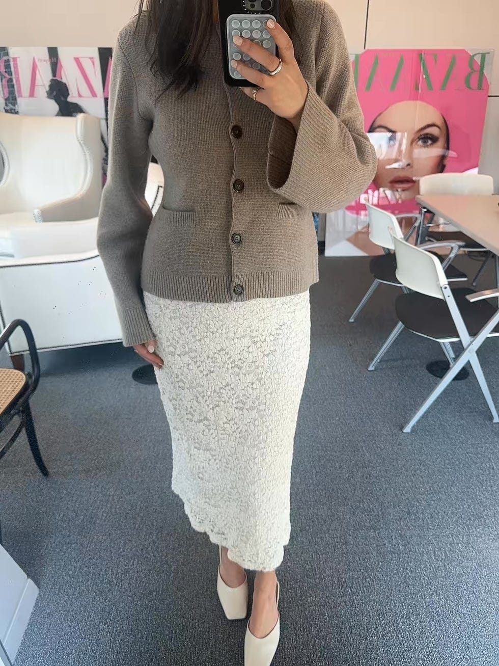 Une personne présentant une tenue élégante composée d'un cardigan brun et d'une jupe en dentelle blanche
