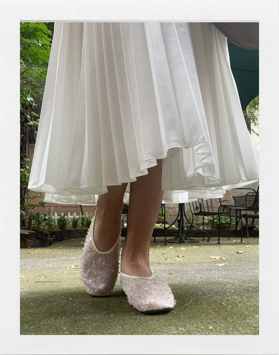 chaussures associées à une robe blanche plissée dans un environnement de jardin