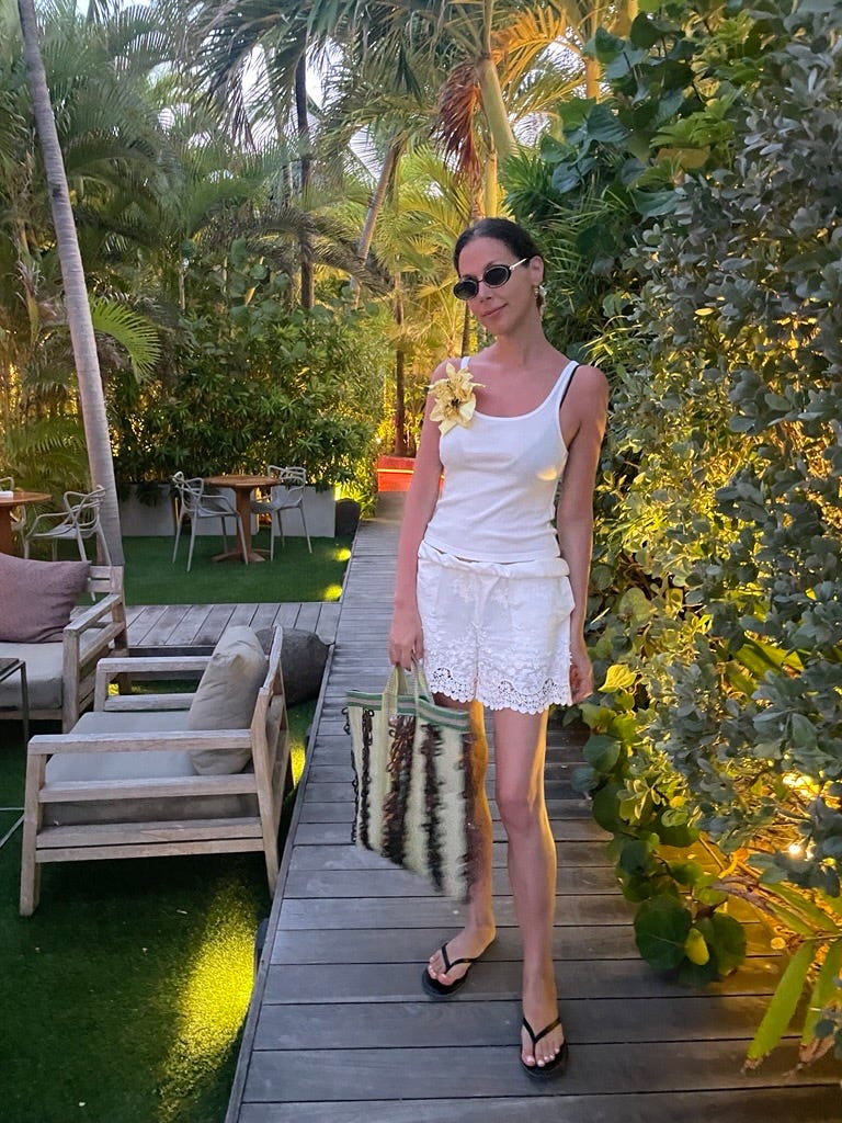 Une femme dans une tenue d'été décontractée pose dans un cadre extérieur luxuriant