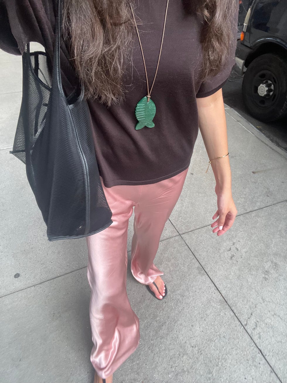 Une personne marchant sur un trottoir portant des vêtements élégants avec des accessoires