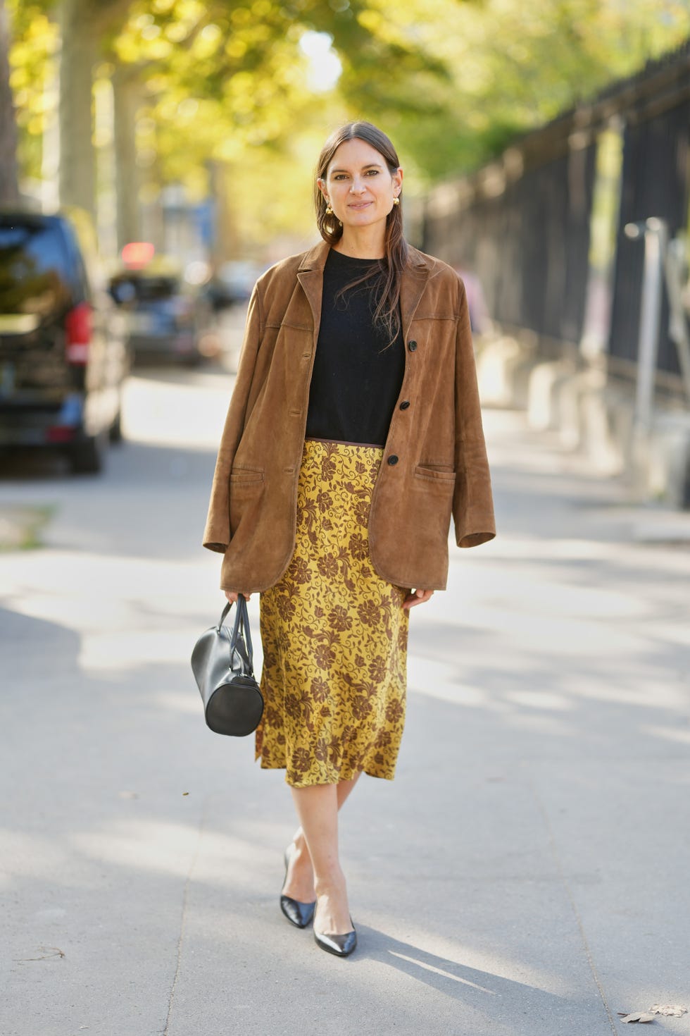 paris, france 30 septembre : lydia zacharis porte une veste en daim marron sur les épaules, un haut noir, une jupe midi à motifs jaunes, des talons chaton noirs et tient un sac à main noir à l'extérieur de dries van noten pendant le printemps été 2026 de vêtements pour femmes dans le cadre de la fashion week de paris le 30 septembre 2025 à paris, france. (photo de 305pics/getty images)