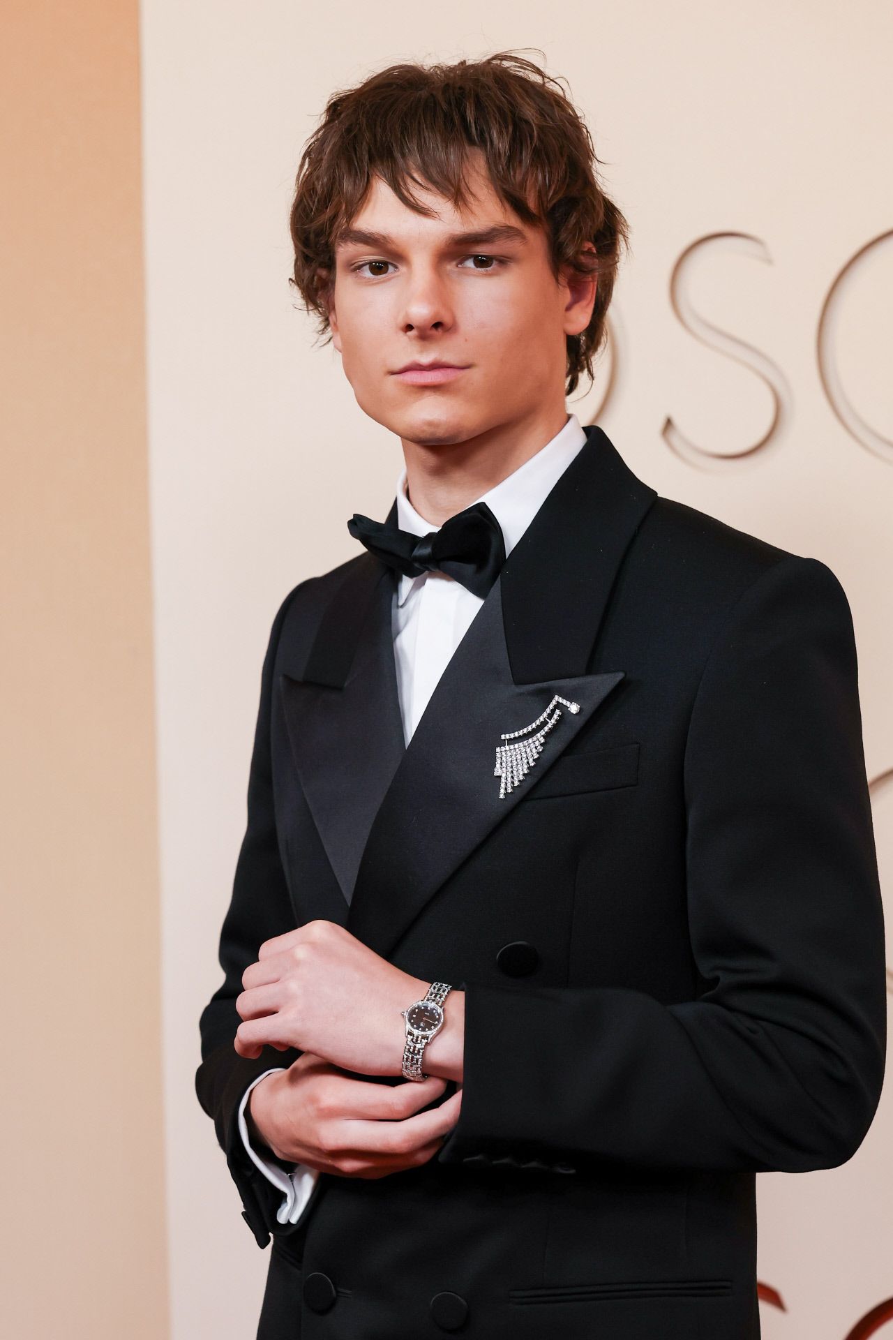 L'acteur Mason Thames choisit une broche pour compléter son look aux Oscars 2026