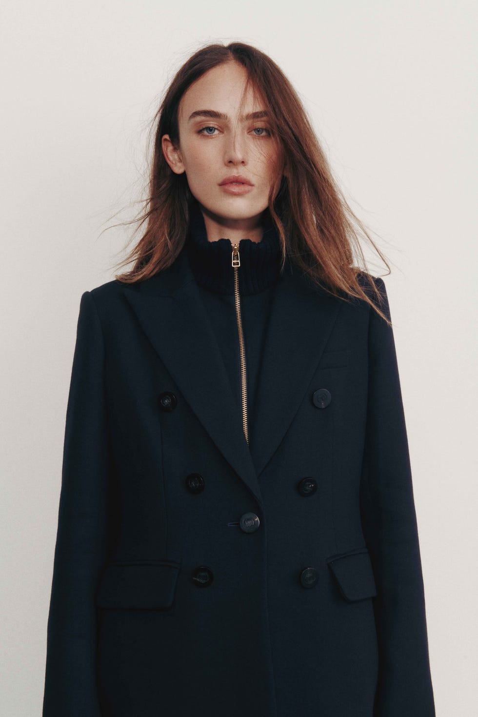 une personne portant un manteau sombre sur mesure avec un pull à col montant en dessous