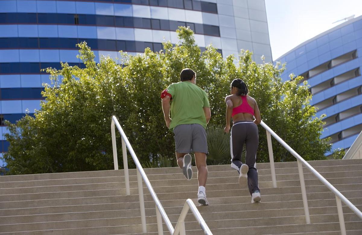 Couple qui monte les escaliers dans un cadre urbain, vue arrière