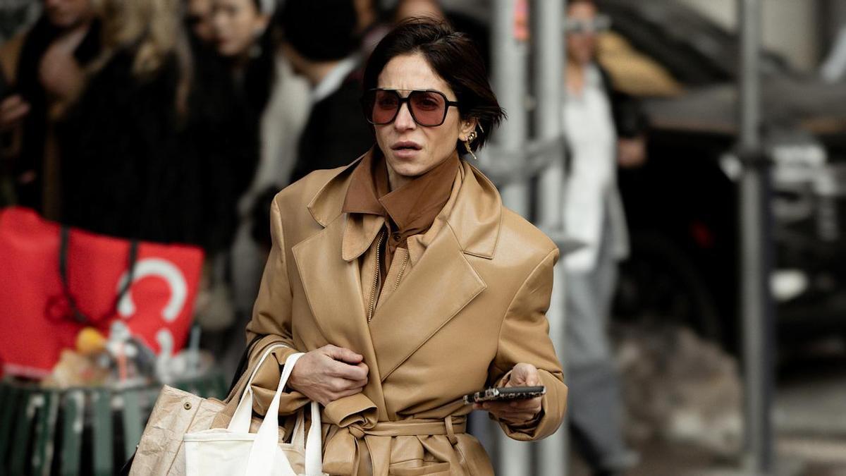 Look de street style que combina una gabardina con unas botas beige