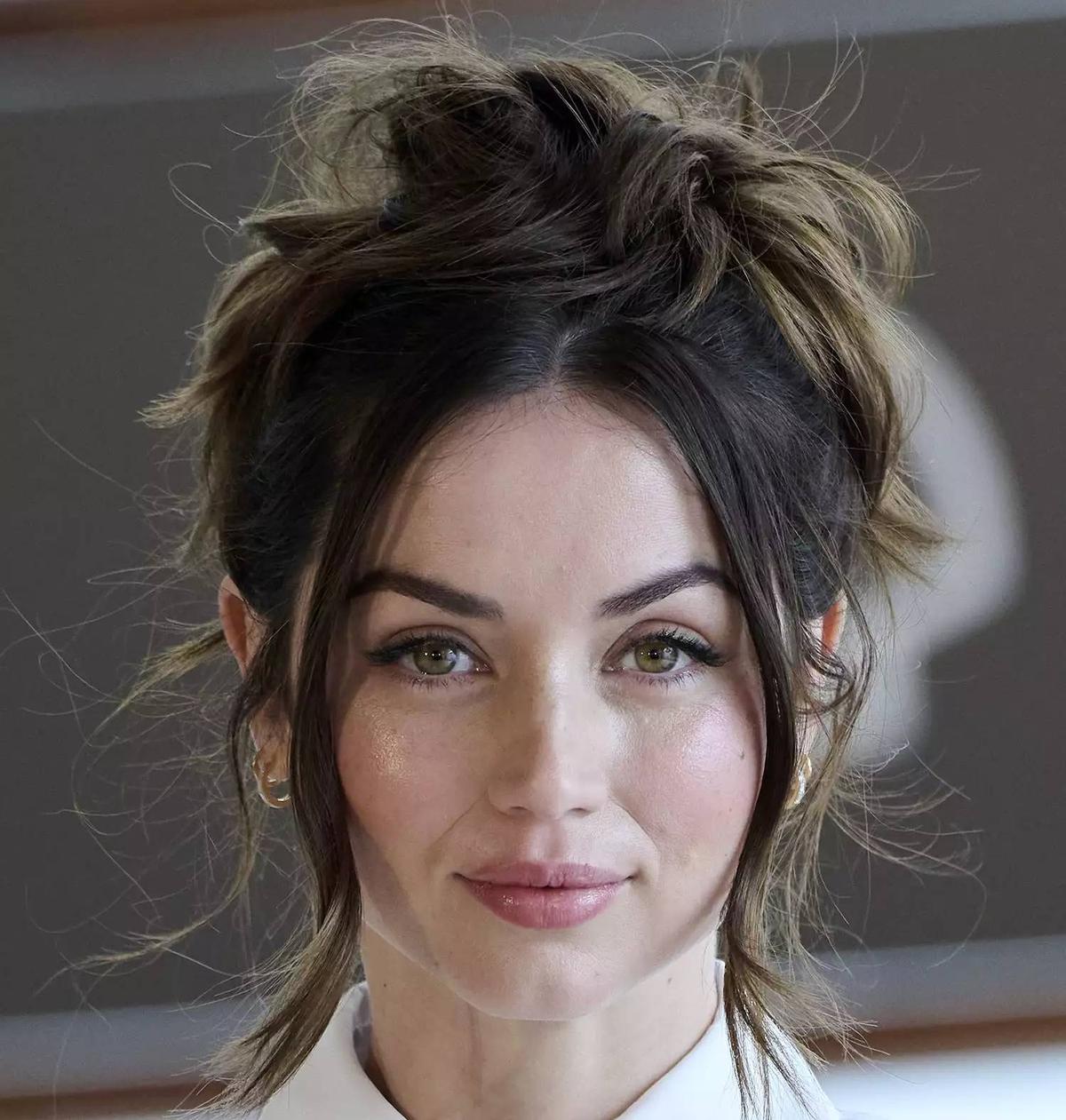 Ana de Armas avec un chignon en désordre avec deux mèches lâches sur les côtés.