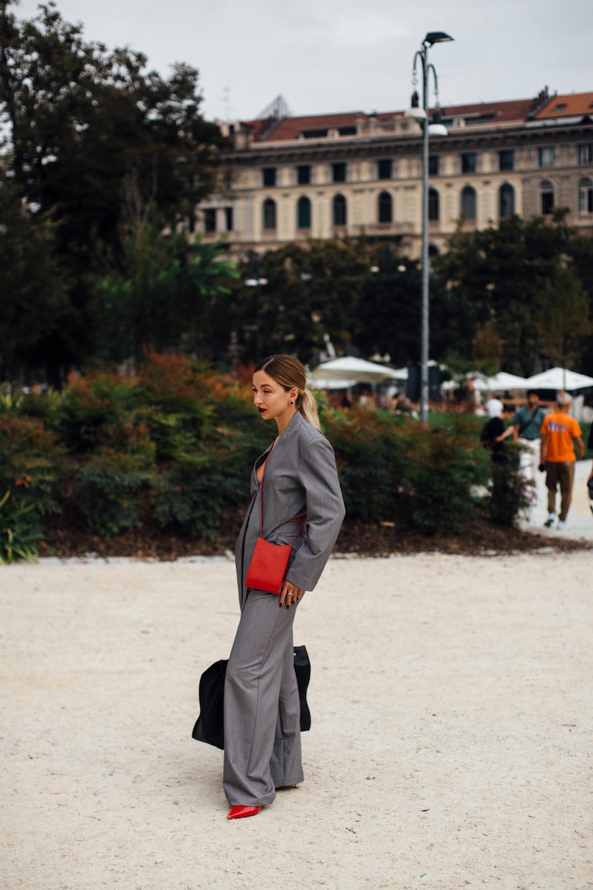 Look street style avec une tenue grise et un sac rouge
