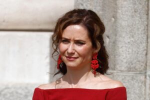 Certificat honorifique pour le look rouge intense d'Isabel Díaz Ayuso lors de la réception Macron : décolleté Bardot, signature espagnole en-tête et détails drapés